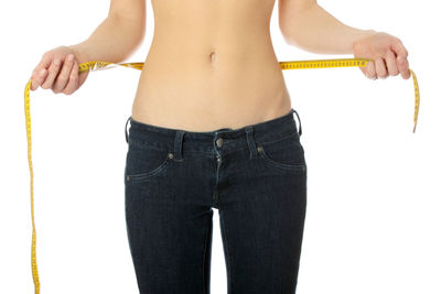 Midsection of shirtless woman against white background