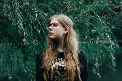 Young woman looking away against plants