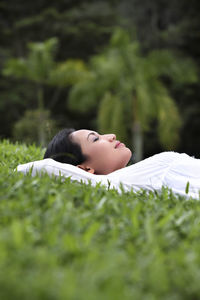 Woman lying on grassy field at park