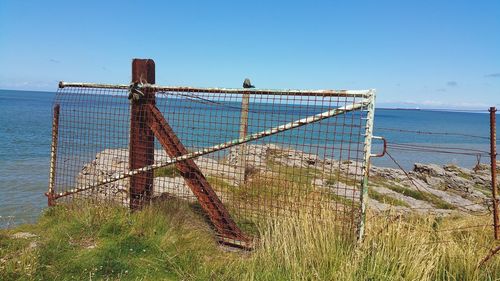 Metallic structure by sea against clear sky