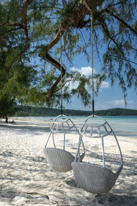 Chair on beach by sea against sky