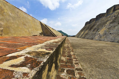 Footpath amidst fortified walls of castillo san felipe de barajas against sky