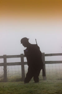 Man standing by railing against sky