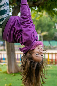 Portrait of smiling girl hanging upside down in park