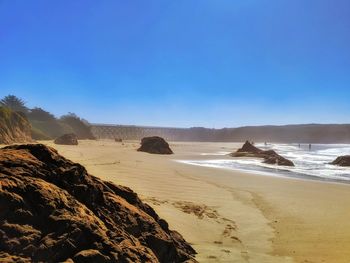 Scenic view of beach against clear blue sky