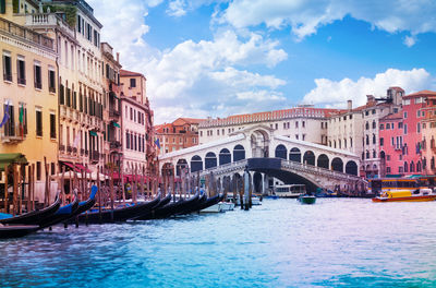 View of canal and buildings against cloudy sky