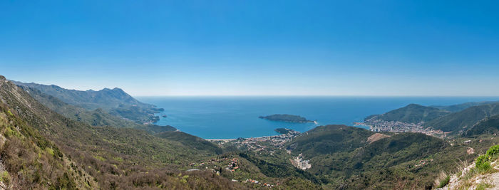 Scenic view of sea and mountains against clear blue sky