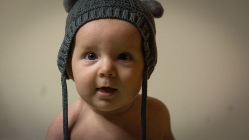 Portrait of cute boy wearing hat against gray background