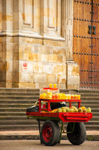 Fruits and juices for sale on cart against historic building at bolivar square