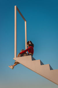 Low angle view of man against clear blue sky