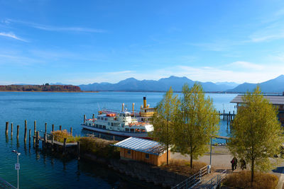 Boats moored at harbor against blue sky