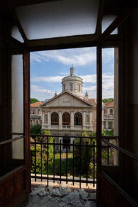 Built structures of a church seen from an open window with broken glass 