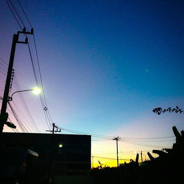 clear sky, sunset, silhouette, building exterior, low angle view, built structure, architecture, copy space, blue, power line, electricity pylon, dusk, sky, outdoors, electricity, cable, city, connection, no people, orange color