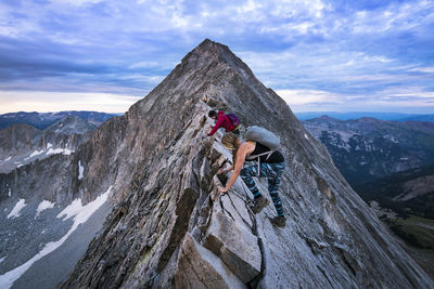 Female hikers climbing mountain against sky during sunset