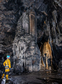 Woman standing against rock formations in cave