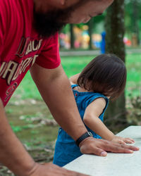 Rear view of father and toddler daughter outdoors.