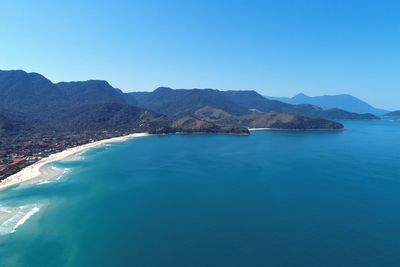 Scenic view of sea and mountains against clear blue sky