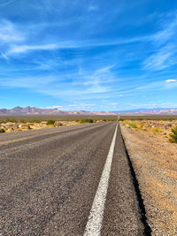 Road leading towards landscape against sky