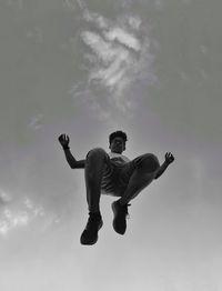 Low angle view of man jumping against sky