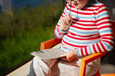 Elderly woman in glasses sitting on balcony near the sea