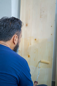 Rear view of man looking through window