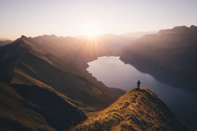 Man standing on cliff looking down on mountain lake