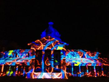 Illuminated carousel in amusement park against sky at night