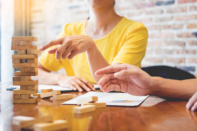 Midsection of colleagues discussing over dominoes at desk in office