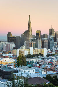 Buildings in city against clear sky during sunset