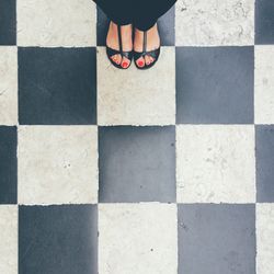 Low section of woman standing on checked flooring