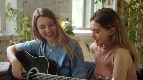 Lesbian couple playing guitar at home