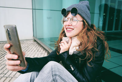 Young woman using mobile phone while sitting in laptop