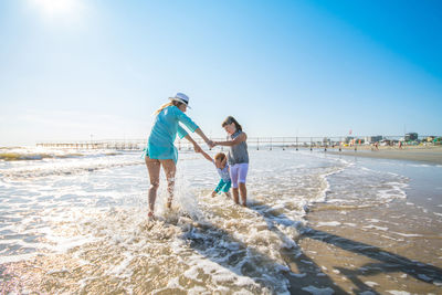 Happy family enjoying at beach against sky