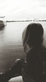 Girl looking at ships against cloudy sky