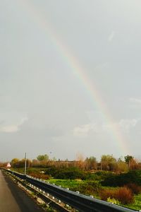 Rainbow over road against sky