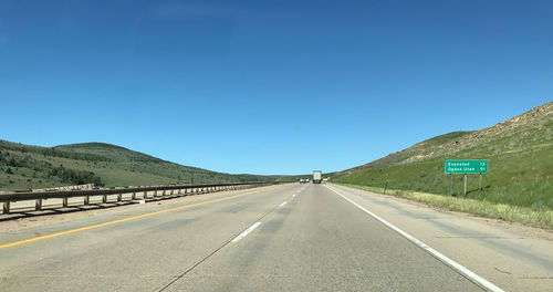 Empty road against clear blue sky