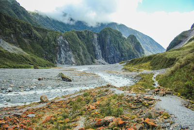 Scenic view of river flowing amidst mountains against sky