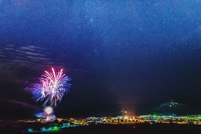 Firework display over sea against sky at night