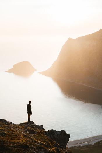 Man standing on rock over sea against sky