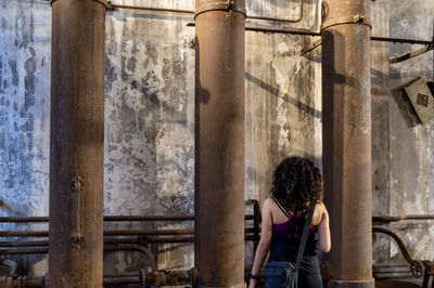 Back view of a woman exploring an old abandoned factory.