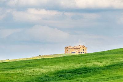 Building on field against cloudy sky