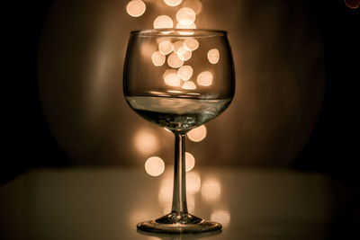 Close-up of wineglass against illuminated light