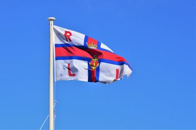 Low angle view of flag against blue sky