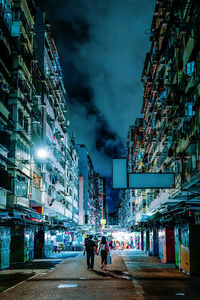 People walking on street amidst buildings against sky