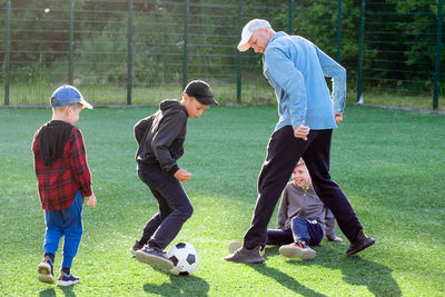 Rear view of boy playing soccer at park