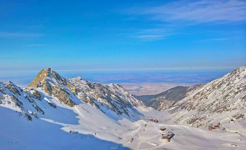 Scenic view of snowcapped mountains against blue sky