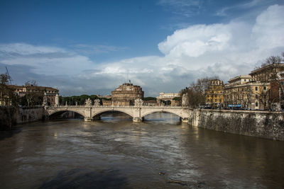 Arch bridge over river against buildings in city