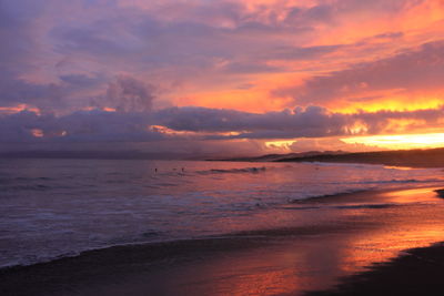 Scenic view of sea against dramatic sky at sunset