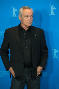 Midsection of man with arms raised standing against blue background