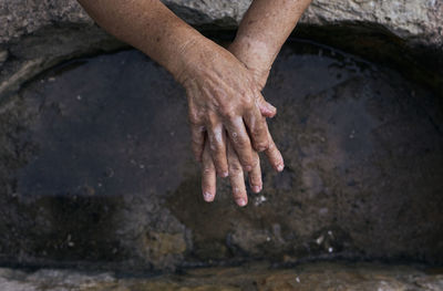 High angle view of hands on wet shore